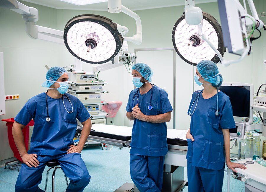 Three surgeons have a discussion in the OR.