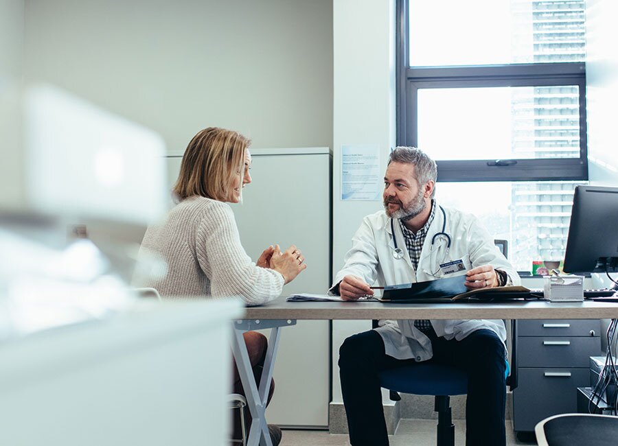 A doctor at a desk having a conversation.